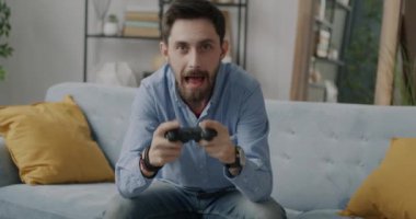 Video oyunu oynayan duygusal adamın portresi joystick kullanarak apartmandaki kameraya bakarken eğleniyor. Teknoloji ve eğlence konsepti.