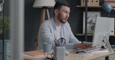 Ofiste masa başında klavyeyle yazı yazan ciddi bir çift ırklı adam. Profesyonel meslek ve insan konsepti.
