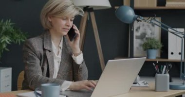 Ofis müdürünün portresi cep telefonuyla konuşuyor ve iş geliştirmeye odaklanmış bir laptop ile daktilo ediyor. Halk ve kariyer kavramı.