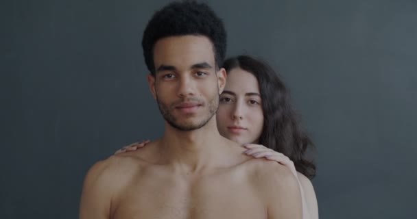 幸せな出産のカップルの服を一緒に灰色の色の背景に笑みを浮かべてカメラを見て立っている 愛と親密さの概念 — ストック動画