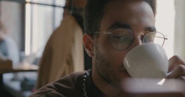 Afro-Amerikalı neşeli öğrencilerin yakın plan portresi kahve içerken ve gündüz kafede akıllı telefon kullanırken. İçecek ve gençlik kavramı.