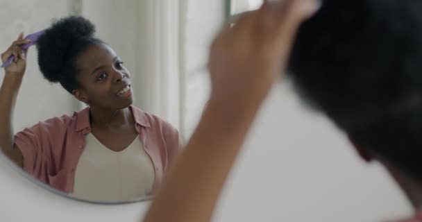 Young African American Woman Combing Hair Looking Reflection Mirror Bathroom — Stock Video