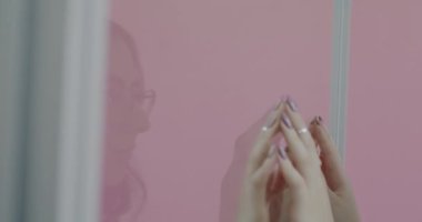 Birbirlerinin önünde duran ve pembe arka planda el ele tutuşan üzgün çift. İlişki sorunları ve insanların kavramı.