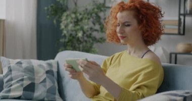 Akıllı telefonla oynayan kadın oyuncunun portresi evde eğleniyor. Modern aygıt ve eğlence konsepti.