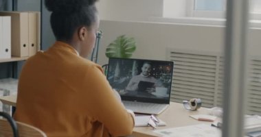 Afrikalı Amerikalı bir kadın internette iş arkadaşlarıyla konuşurken bilgisayarla konuşuyor. Profesyonel iletişim ve işyeri kavramı.