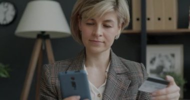 Genç iş kadını akıllı telefon ve kredi kartıyla online ödeme yapıyor. Finans ve modern teknoloji kavramı.