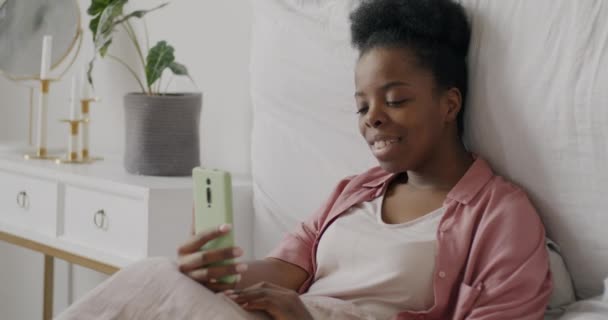 침대에서 스마트 카메라를 포즈를 취하는 매력적 아프리카 미국인 여성의 움직임 — 비디오