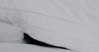 Evdeki battaniyenin altında yatıp gülümseyen mutlu Afrikalı Amerikalı kızın portresi. Yatak ve konfor kavramı.