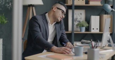 İş adamının portresi cep telefonuyla konuşuyor ve ofiste yazmakla meşgul. Modern teknoloji ve iletişim konsepti.