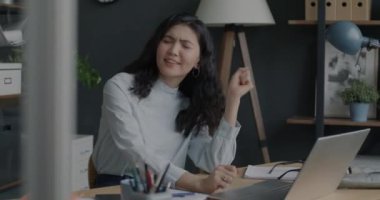Ofiste iş yerinde müzik dinleyen neşeli Asyalı bir çalışanın portresi. Olumlu duygu ve eğlence kavramı.
