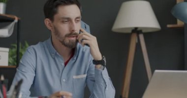 Genç girişimci cep telefonuyla danışmanlık yapıyor. Ofiste çalışan dizüstü bilgisayara bakıyor. İletişim ve iş tartışma kavramı.