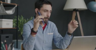 Tasasız ofis çalışanının, kulaklıkla müzik dinleyen ve iş yerinde dans eden yavaş çekim portresi. Mola ve eğlence konsepti.