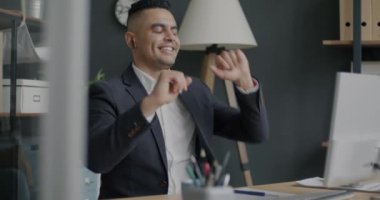 Keyifli Orta Doğulu iş adamı ofiste çalışırken dans edip eğleniyor. Pozitif duygu ve rahatlama kavramı.