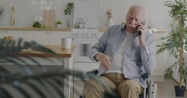 Cep telefonuyla konuşan son sınıf öğrencisinin portresi tekerlekli sandalyede oturuyor. Yaşlılar için iletişim ve modern teknoloji.