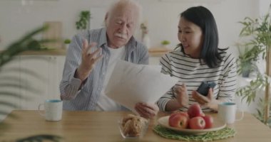 Üst düzey bir adama evrak işlerinde yardım etmek için gönüllü olan ve mutfaktaki akıllı telefon faturalarını ödeyen biri. Emeklilik ve hemşire hizmeti kavramı.