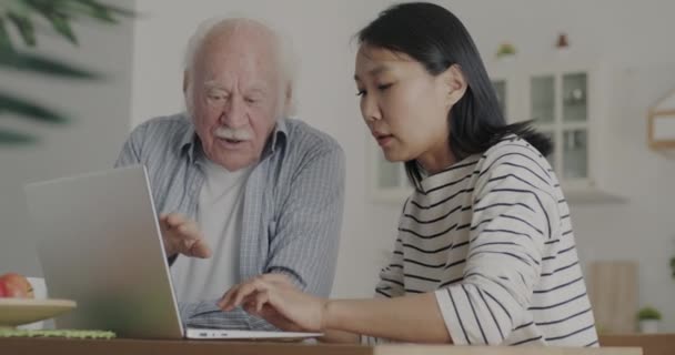 Amable Cuidador Asiático Enseñando Hombre Mayor Utilizando Escritura Computadoras Hablando — Vídeo de stock