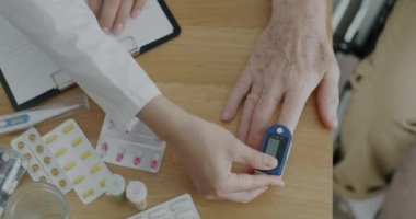 Elektronik oksijen doygunluk monitörüyle hasta elinin yakın görüntüsü ve kapalı alandaki ölçümleri kontrol eden bir doktor. Sağlık teknolojisi ve tıp konsepti.