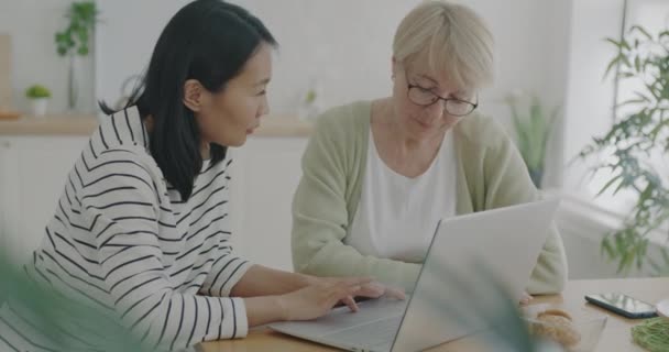 Женщина Волонтер Помогает Пожилой Женщине Ноутбуком Обучение Технологии Говорить Использовать — стоковое видео