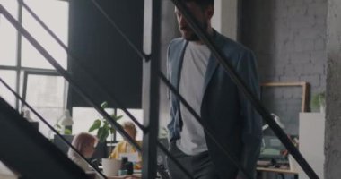 Üst katta iş yerinde akıllı telefon kullanarak yürüyen genç işadamlarının yavaş çekimleri. İş bürosu içi ve insan konsepti.