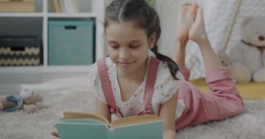 Tasasız çocuk portresi evde yerde yatan hikayeye odaklanmış gülümseyen bir kitap. Çocukların gelişimi ve eğitim edebiyatı kavramı.