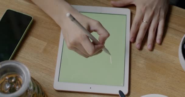 カフェテーブルでは グラフィックタブレットやデジタルペンで屋内で女性の手描きのクローズアップ 現代の技術とプロの機器の概念 — ストック動画