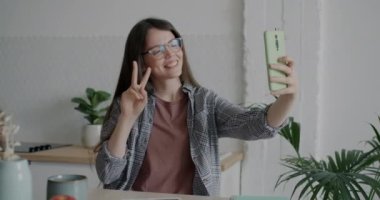 Akıllı telefon kamerası için poz veren neşeli kızın portresi mutfaktaki sosyal medya için selfie çekiyor. Modern yaşam tarzı ve tasasız gençlik kavramı.