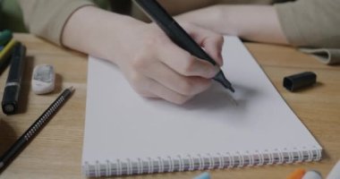 Kadın el çizimlerini kağıt üzerine kalemle yakın plan çekerken kadın da kapalı masa hobisinin keyfini çıkarıyor. Sanat ve yaratıcı aktivite kavramı.