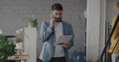 Ofiste iş arkadaşlarıyla telefonda konuşan ve iş arkadaşlarıyla konuşan girişimcilerin yavaş çekim portresi. İş ve iletişim kavramı.