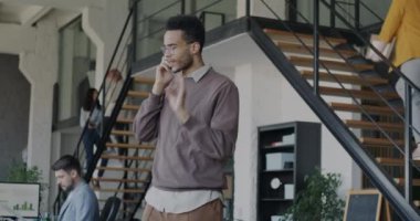 Afrika kökenli Amerikalı bir ofis çalışanı cep telefonuyla konuşuyor yoğun bir iş yerinde müşteriyle anlaşma yapıyor. Şirket ve personel kavramı.