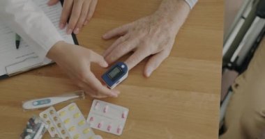 Doktorun oksijen doygunluğunu elektronik cihazla kontrol etmesi ve klinikte tıbbi kayıtlar yazması. Sağlık ve ekipman konsepti.
