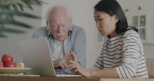 Profesjonalny Opiekun Rozmawiający Seniorem Wykorzystujący Laptopa Uczący Nowoczesnej Technologii Domu — Wideo stockowe