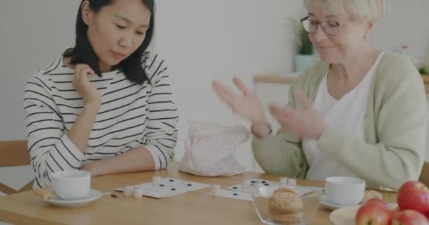 Vrouwelijke Vrijwilliger Spelen Lotto Spel Met Senior Vrouw Plezier Lachen — Stockvideo