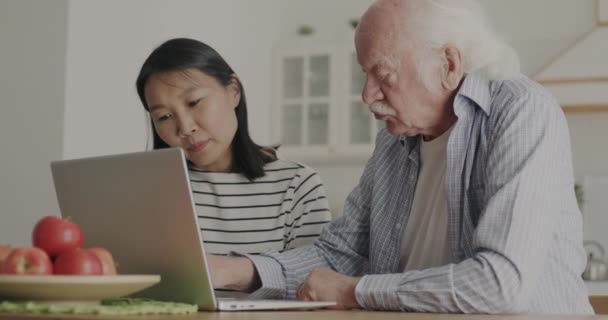 Bakıcı Kız Yaşlı Babaya Dizüstü Bilgisayar Kullanmayı Öğretiyor Mutfakta Bilgisayarla — Stok video