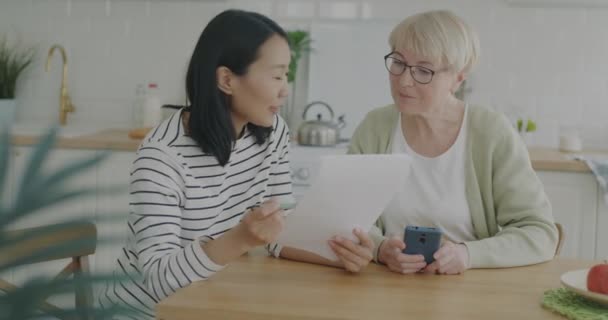Young Woman Helping Senior Pensioner Paperwork Paying Bills Talking Kitchen — Stock Video