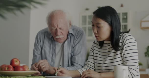 Bakıcı Hemşire Yaşlı Adama Evrak Işlerinde Yardım Ediyor Evde Akıllı — Stok video