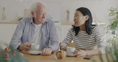 Yaşlı adam ve genç kadın çay içip sohbet ediyorlar. Mutfakta yemek yiyip sohbet ediyorlar. Boş zaman ve aile ilişkisi kavramı.