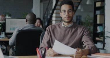 Afrikalı Amerikalı iş adamının portresi çevrimiçi video görüşmesi yapıyor ve paylaşılan ofiste kağıtları gösteriyor. İş iletişimi ve ortak çalışma kavramı.