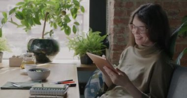 Tablet çizen ve gülümseyen neşeli dijital kadın sanatçı rahat bir kafede sergileniyor. Modern yaşam tarzı ve uzak çalışma konsepti.