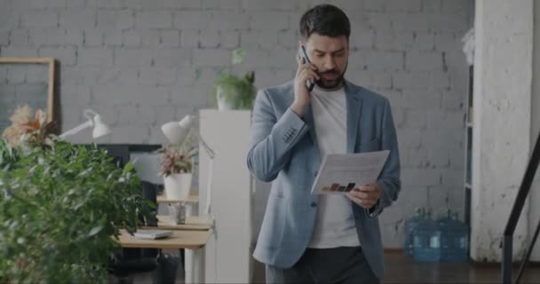 Ofiste Yürüyen Cep Telefonuyla Konuşan Arkadaşlarını Selamlayan Bir Çalışanın Portresi — Stok video