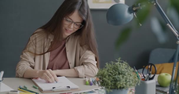 机に一人で座っている現代のオフィスで働く創造的なデザイナーの絵を描く クレヨンと紙を使って美しい女性が芸術に集中 — ストック動画