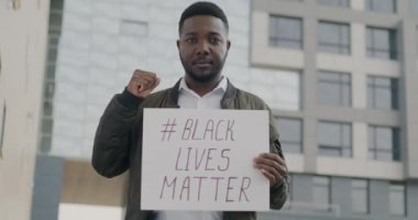 Siyahi Yaşamlar Önemlidir posterini taşıyan Afrikalı Amerikalı aktivistin portresi şehirdeki ırkçılığı protesto ediyor. Irksal eşitlik ve insan konsepti.
