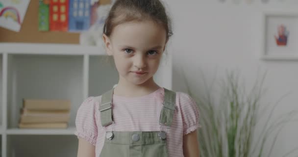 幸福を表す保育室に立って親指アップ手ジェスチャーを示す恥ずかしがり屋の子供のスローモーション肖像画 子供時代と満足の概念 — ストック動画