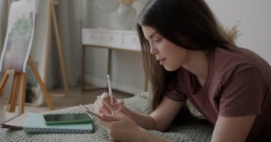 Dijital grafik tabletli yaratıcı bayan gülümseyerek evde yatakta uzanan hobisinin keyfini çıkarıyor. Eğlence ve milenyum konsepti.