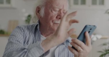 Son sınıf öğrencisi akıllı telefon mesajları kullanıyor gülümsüyor ve evdeki modern mutfakta iyi haberlerin tadını çıkarıyor. Mobil uygulama ve yaşlılar konsepti.