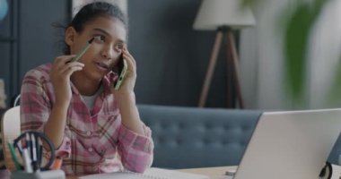Cep telefonuyla konuşan neşeli melez kız ve ev ödevlerini evde konuşmakla meşgul. Gençlik ve iletişim kavramı.