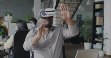 Ofiste sanal gerçeklik gözlüğü kullanan Afro-Amerikalı bir adam ara sırasında el sıkışarak eğleniyor. Modern teknoloji ve eğlence konsepti.
