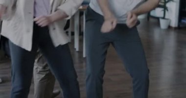 Erkek ve kadın meslektaşlar iş partisinde birlikte dans edip müzik ve kurumsal eğlencenin tadını çıkarıyorlar. Eğlence ve işyeri konsepti.