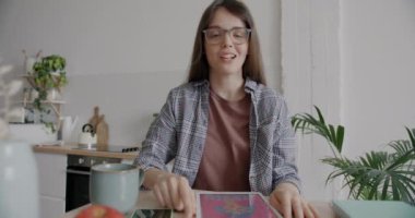 Güzel bir kadının portresi mutfakta çevrimiçi video görüşmesi sırasında resimli tablet ekranı gösteriyor ve konuşuyor. İletişim ve tasarım kavramı.