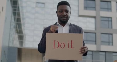 Kendine güvenen Afro-Amerikan bir adamın yavaş çekimde çekilmiş portresi, şehirde ayakta durmak için ilham verici ve destekleyici bir işaret. İnsanlar ve olumlu duygu kavramı.