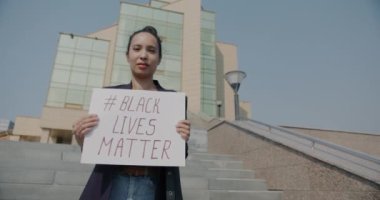 Siyah Yaşamlar Madde 'sini elinde tutan kadın aktivist melez kadının yavaş çekimde çekilmiş portresi. Halk ve ırkçılık sorunu kavramı.